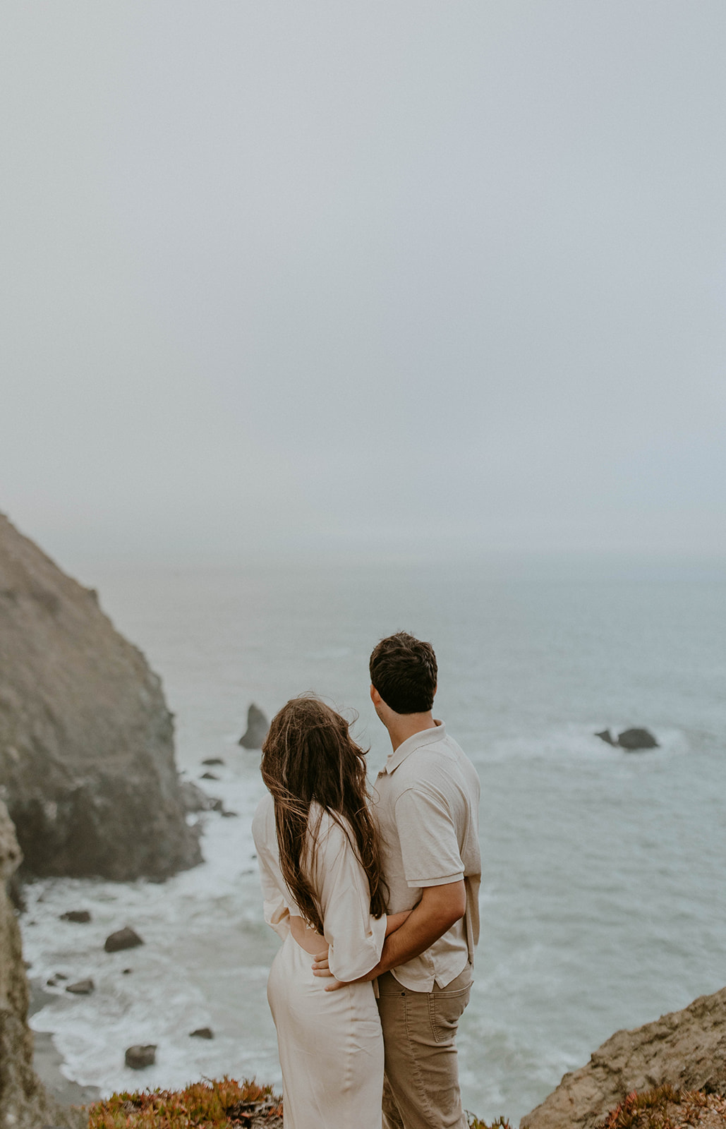 a couple gazes out at the ocean during their fall engagement photos in san francisco
