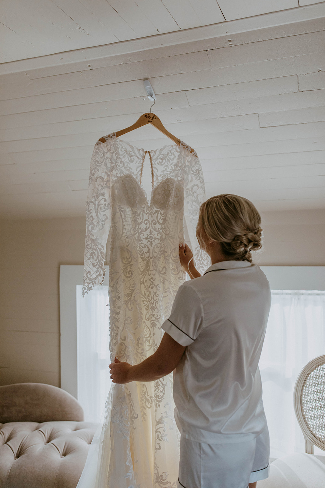 a bride looks at her long sleeve lace western wedding dress as she's getting ready on her wedding day. photo by codi baer photography
