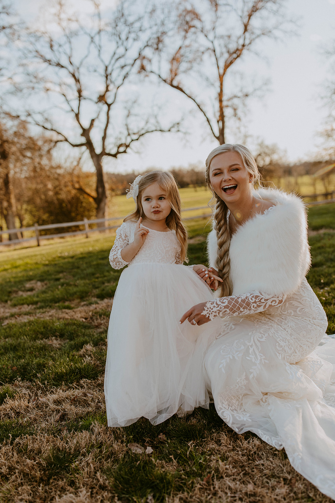 a bride poses for a cute photo with her flower girl at an outdoor winter wedding ceremony
