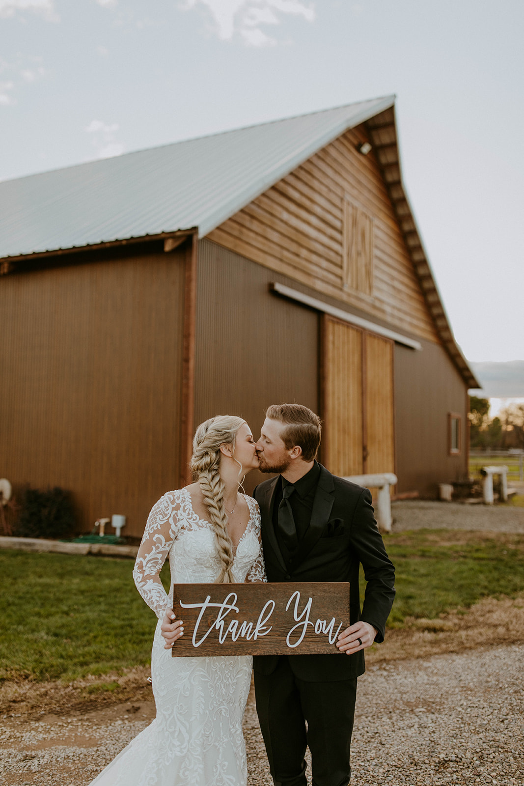 a bride and groom kiss while holding a thank you sign at this western winter wedding

