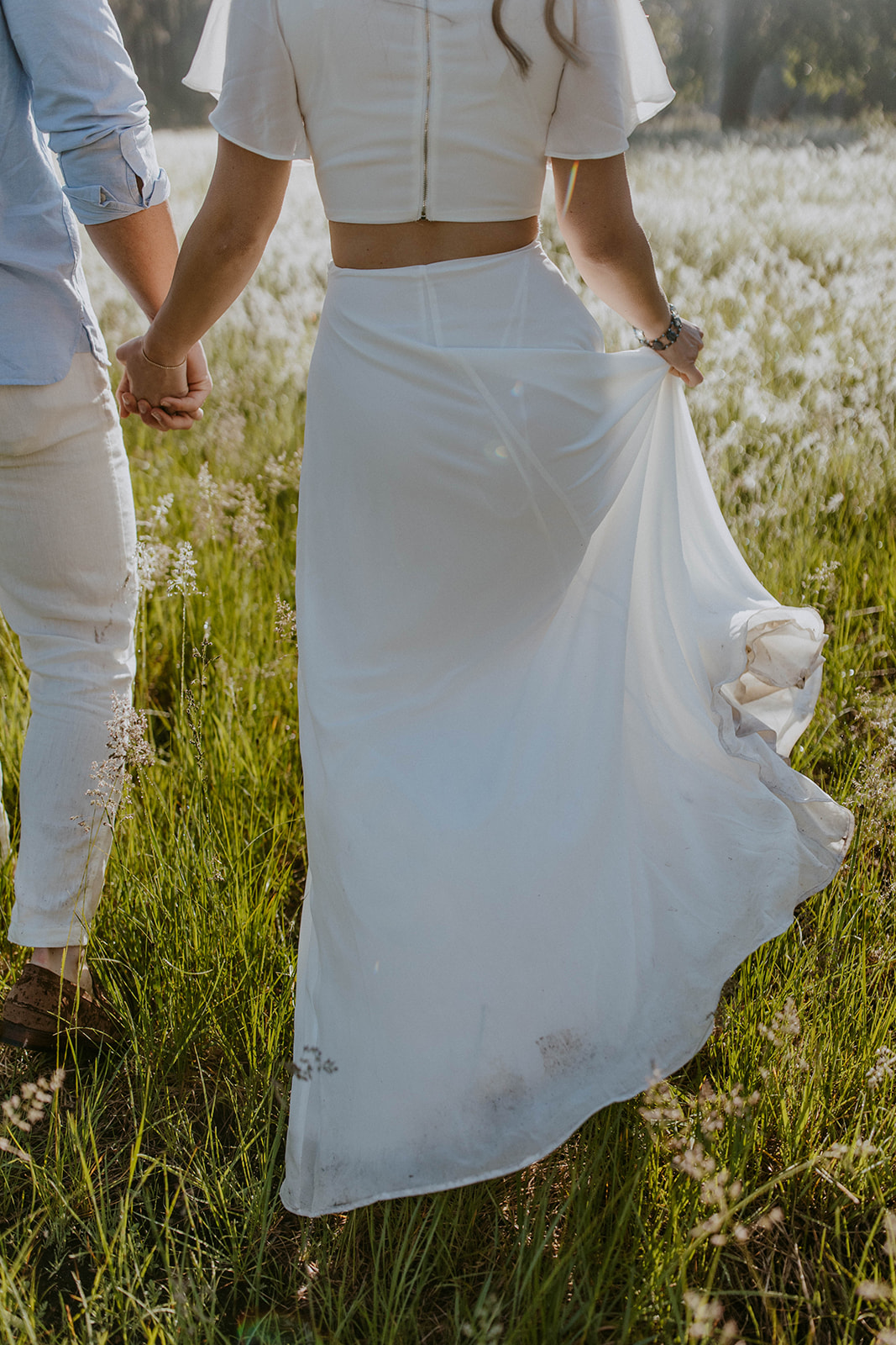 closeup of bride's white skirt during a summer engagement photoshoot in a field of flowers