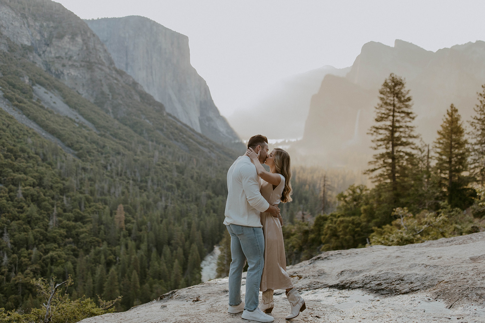 a couple kisses during their yosemite engagement photoshoot overlooking tunnel view