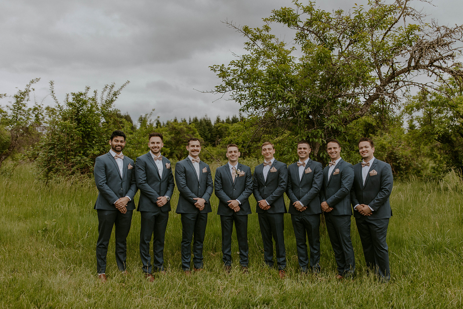 groomsmen pose in a field during a portland oregon wedding